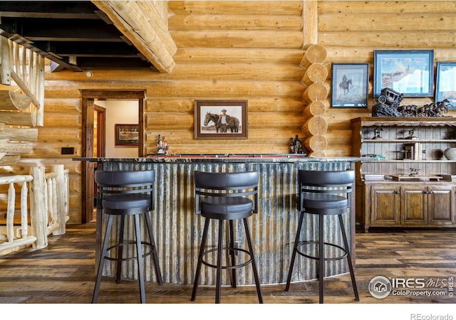 bar with rustic walls and dark wood-type flooring