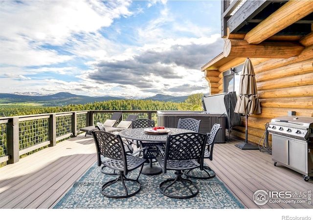 wooden deck featuring a mountain view, a hot tub, and a grill