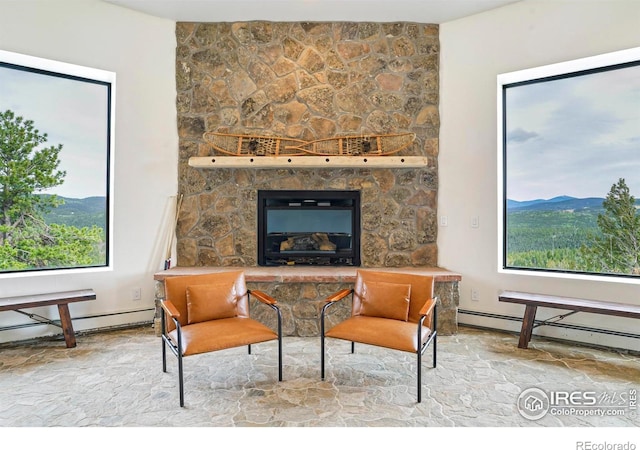 interior space featuring a stone fireplace, a mountain view, and a baseboard radiator