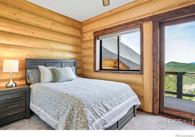 carpeted bedroom with log walls, a mountain view, and ceiling fan