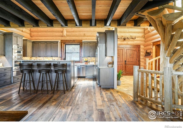 kitchen with a kitchen breakfast bar, a kitchen island, rustic walls, and dark wood-type flooring