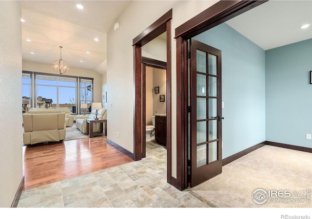 hall featuring vaulted ceiling, an inviting chandelier, and light hardwood / wood-style flooring