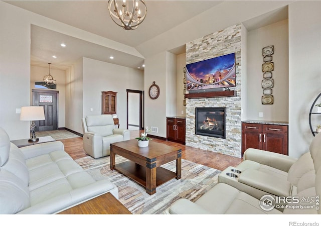 living room with a fireplace, light hardwood / wood-style flooring, and an inviting chandelier