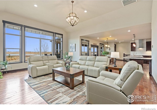 living room with a notable chandelier, light hardwood / wood-style floors, and sink