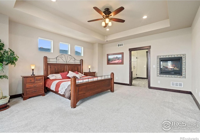 bedroom featuring light colored carpet, a raised ceiling, and ceiling fan