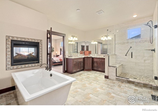 bathroom featuring independent shower and bath, vanity, and a chandelier