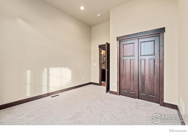 unfurnished bedroom featuring a closet and light colored carpet