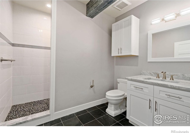 bathroom featuring tile patterned floors, vanity, tiled shower, and toilet