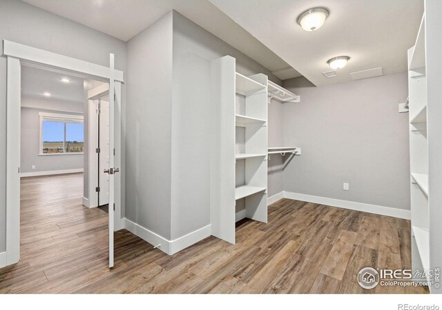 walk in closet with light hardwood / wood-style flooring