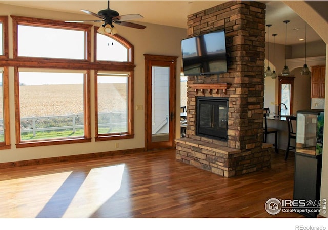 unfurnished living room with dark hardwood / wood-style floors, ceiling fan, and a fireplace