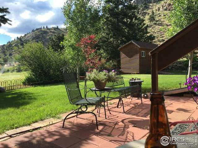 view of patio with an outbuilding, fence, and a mountain view