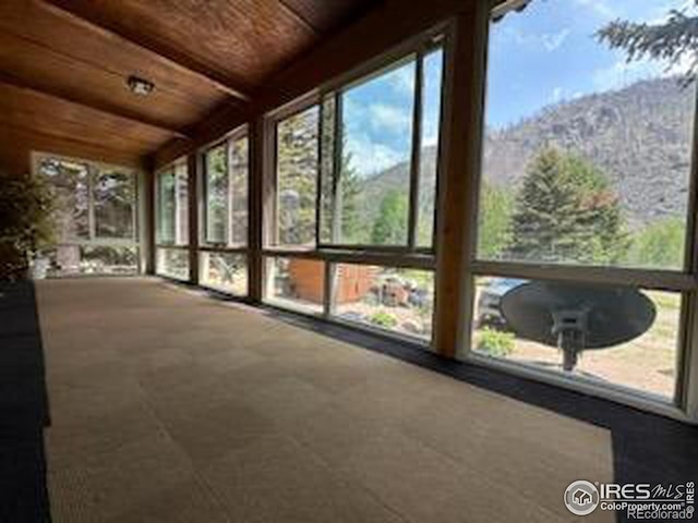 unfurnished sunroom featuring a mountain view and wooden ceiling