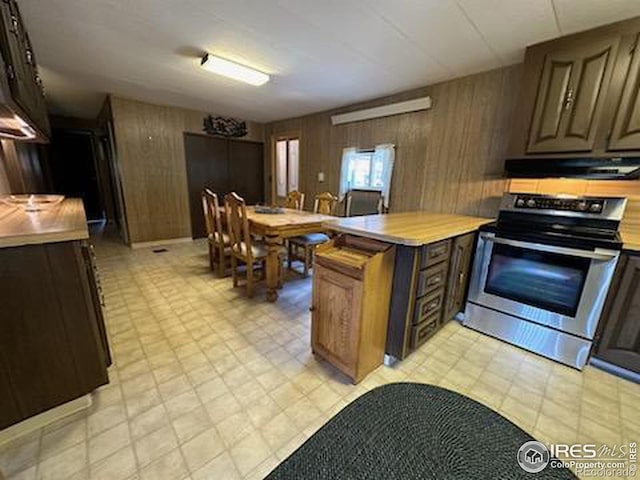 kitchen with wood walls, extractor fan, and stainless steel range oven