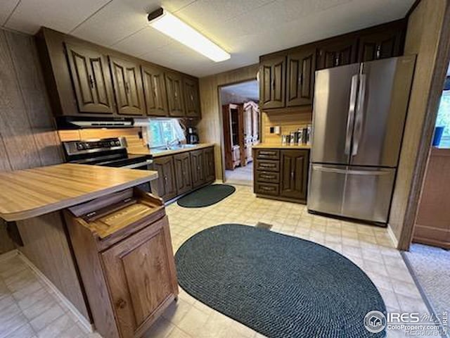 kitchen with a healthy amount of sunlight, kitchen peninsula, appliances with stainless steel finishes, and wooden counters