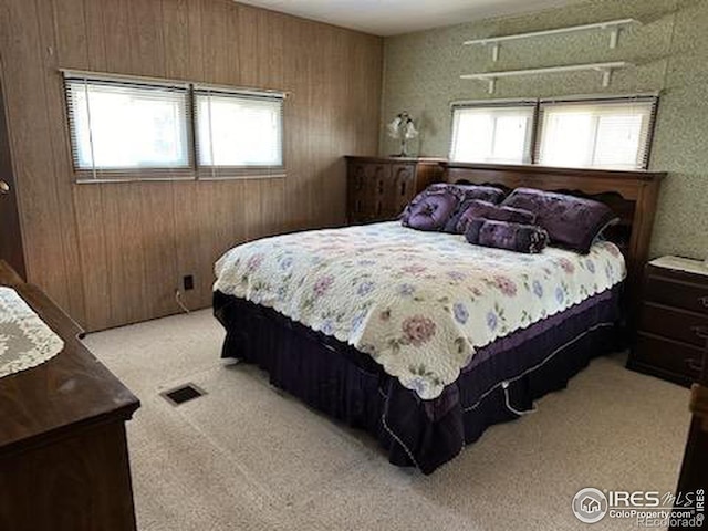 carpeted bedroom with multiple windows and wooden walls