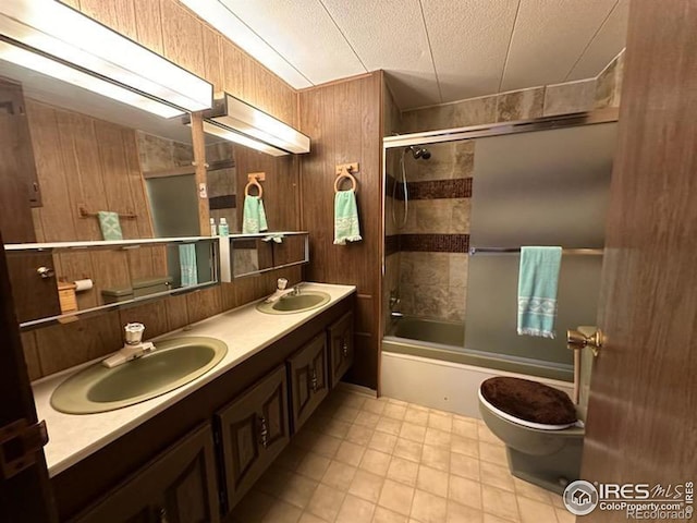 full bathroom featuring vanity, enclosed tub / shower combo, a textured ceiling, and wooden walls