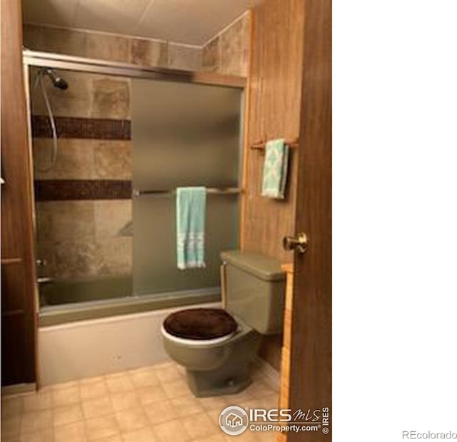 bathroom with toilet and combined bath / shower with glass door