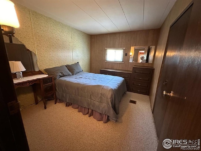 carpeted bedroom featuring wood walls