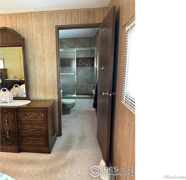 full bathroom with vanity, wood walls, toilet, and combined bath / shower with glass door