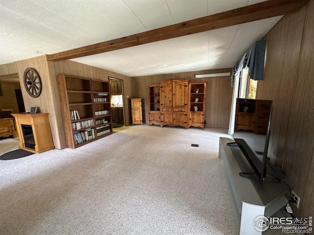 living room with beamed ceiling, wood walls, and light colored carpet