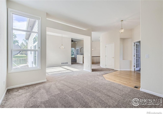 carpeted spare room with a notable chandelier