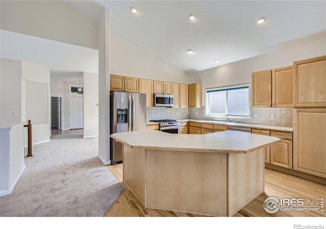 kitchen with appliances with stainless steel finishes, light brown cabinetry, and a center island