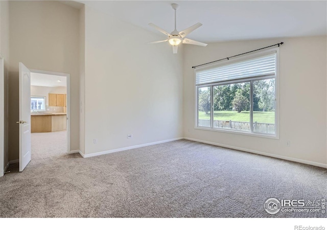 carpeted spare room featuring ceiling fan and high vaulted ceiling