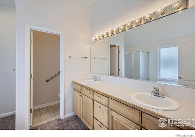 bathroom with vanity, toilet, tile patterned flooring, and a shower with door