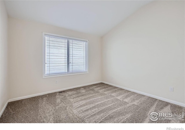 carpeted empty room with vaulted ceiling