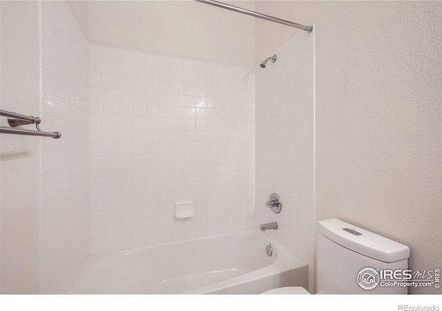 bathroom featuring toilet and tiled shower / bath