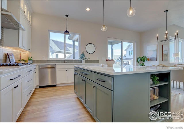 kitchen with white cabinets, stainless steel appliances, a kitchen island, and wall chimney range hood