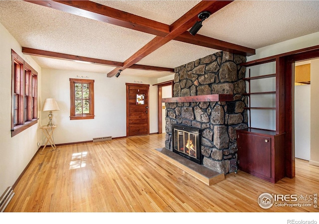 unfurnished living room with a fireplace, a textured ceiling, a baseboard radiator, light hardwood / wood-style flooring, and beamed ceiling