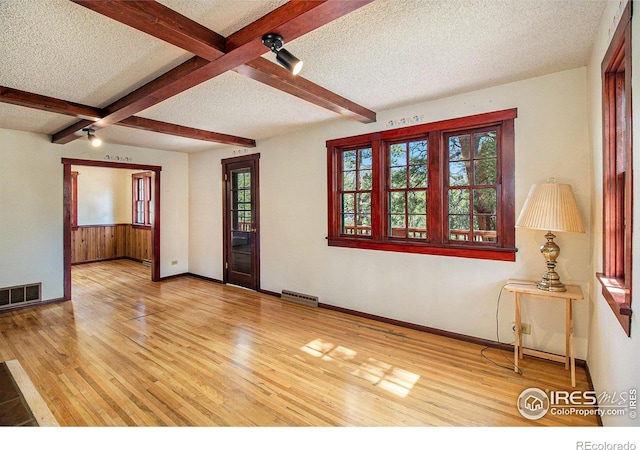 empty room featuring beam ceiling, a textured ceiling, hardwood / wood-style flooring, and ceiling fan