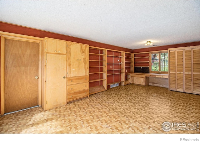 unfurnished living room with a textured ceiling and built in desk