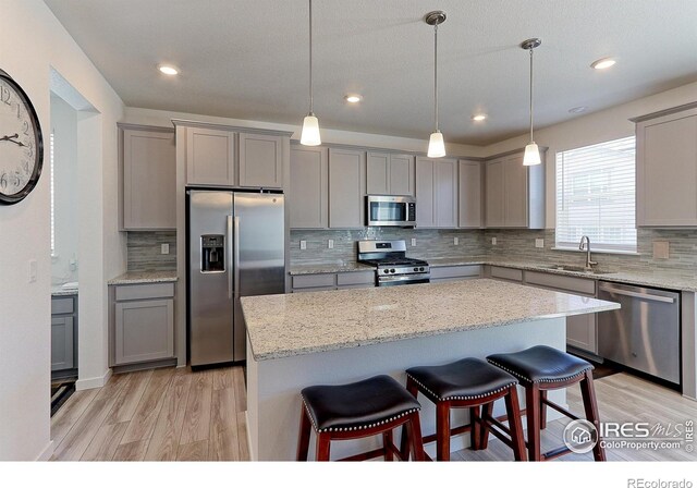 kitchen with a breakfast bar area, sink, stainless steel appliances, and decorative light fixtures