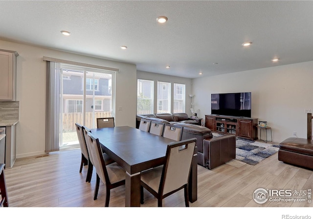 dining area featuring light wood-type flooring and a textured ceiling