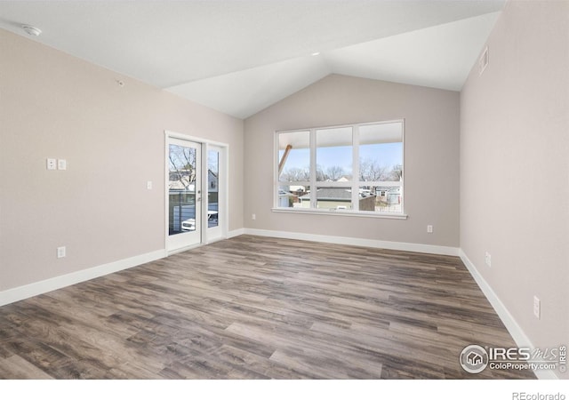 empty room featuring vaulted ceiling and dark hardwood / wood-style floors