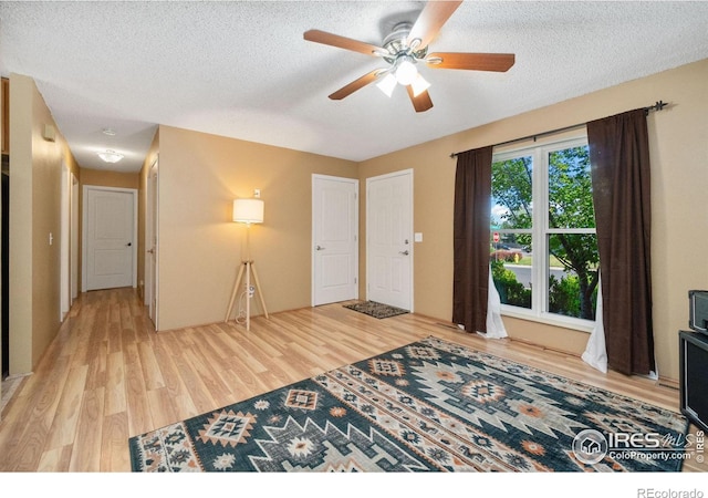 foyer with light wood-style floors, a textured ceiling, and a ceiling fan