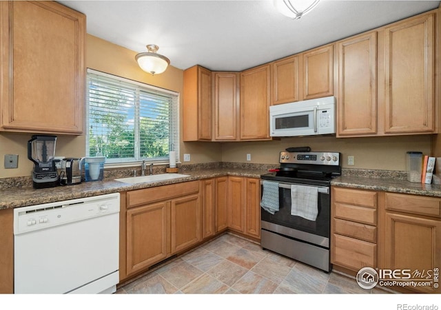 kitchen featuring dark countertops, white appliances, and a sink