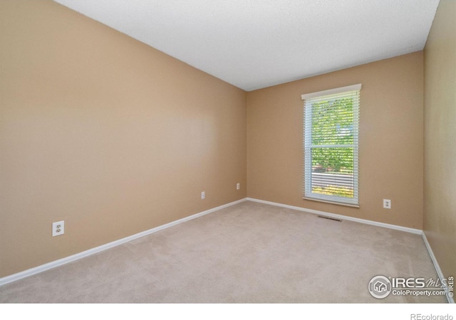 carpeted spare room with visible vents and baseboards