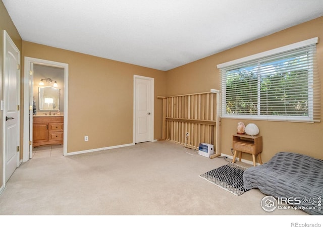 carpeted bedroom featuring baseboards and ensuite bathroom