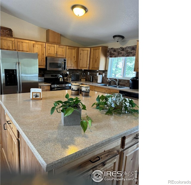 kitchen with vaulted ceiling, appliances with stainless steel finishes, sink, and tasteful backsplash