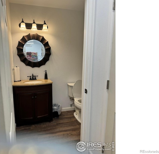 bathroom with wood-type flooring, vanity, and toilet