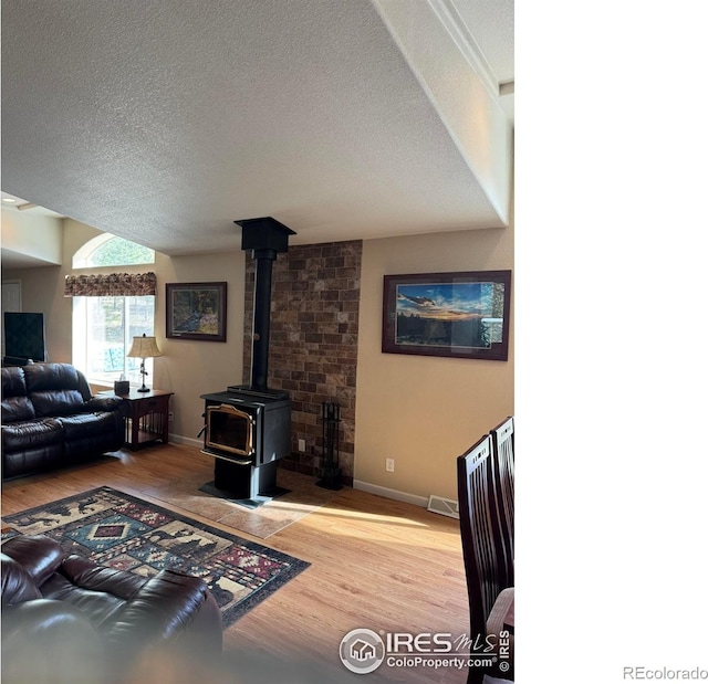 living room with a textured ceiling, hardwood / wood-style floors, and a wood stove