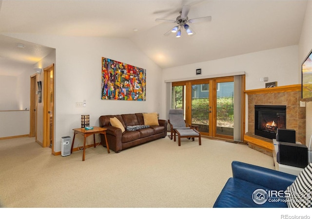 carpeted living area featuring a ceiling fan, baseboards, vaulted ceiling, and a tiled fireplace