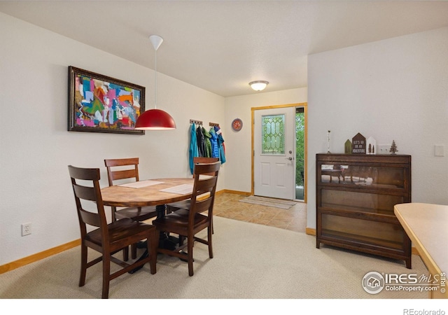 dining space with baseboards and light colored carpet