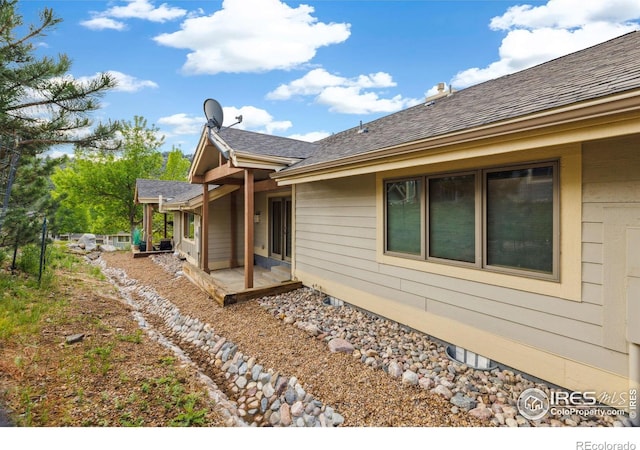 view of side of home with a patio area and a shingled roof