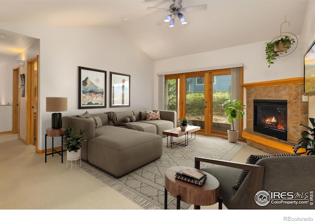 living room with ceiling fan, light colored carpet, a fireplace, baseboards, and vaulted ceiling