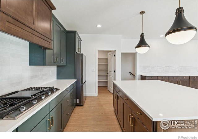 kitchen featuring hanging light fixtures, stainless steel appliances, tasteful backsplash, light hardwood / wood-style floors, and a kitchen island