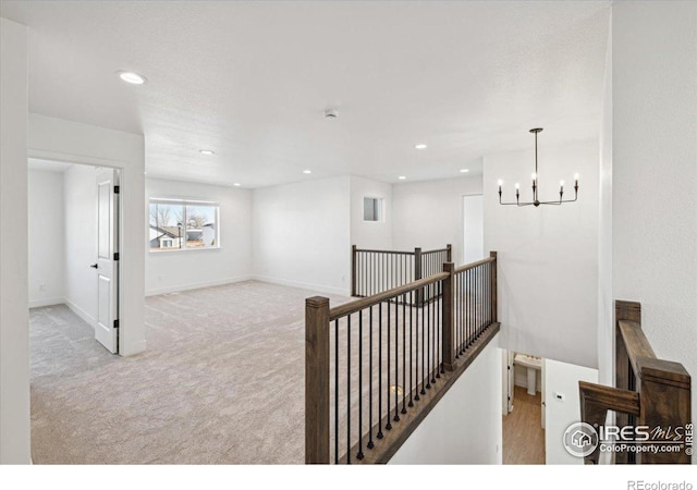 hall with light colored carpet and a chandelier